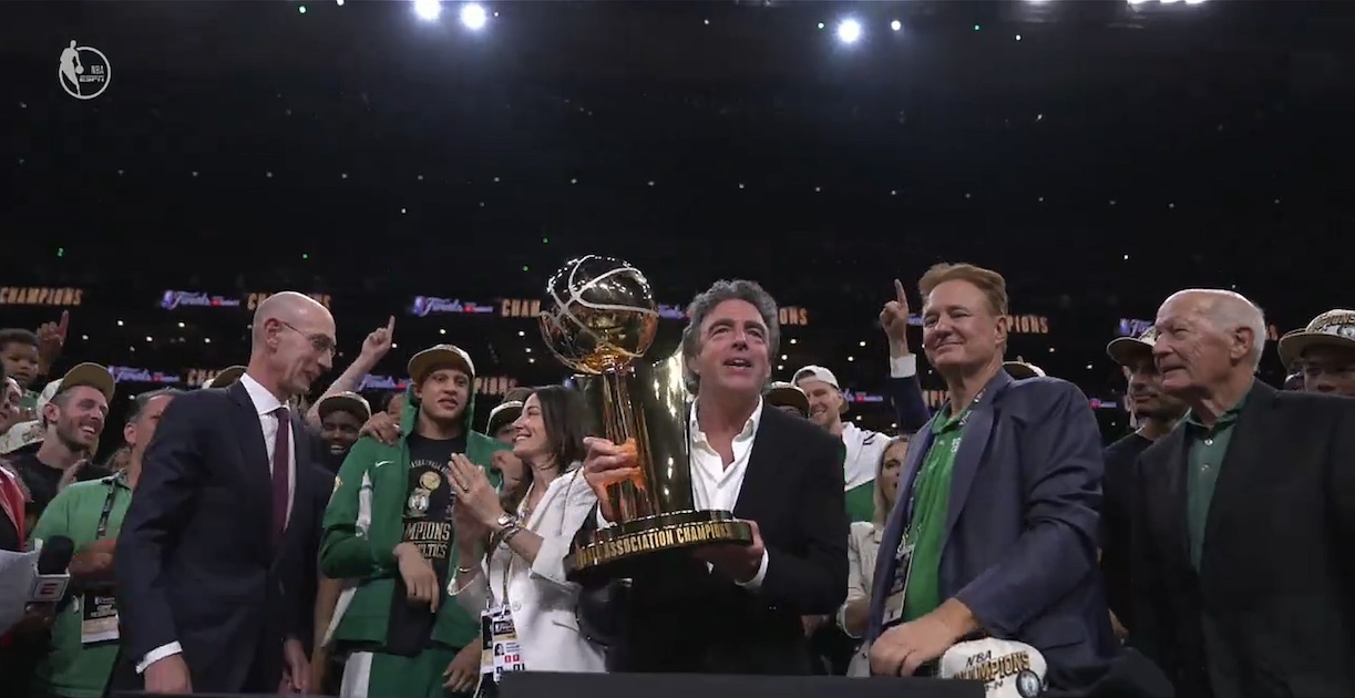 Boston Celtics owners holding up the Larry O'Brien trophy after the victory in the 2024 NBA Finals.